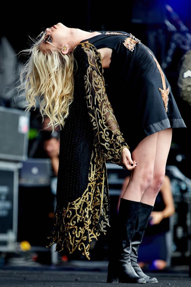 Eine Sängerin mit blonden Haaren beugt sich auf der Bühne nach hinten.
