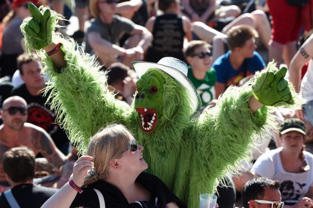 Eine Frau lächelt einen Mann im grünen Monsterkostüm mit Hut an.