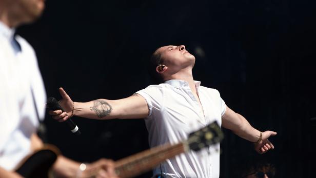 Ein Sänger steht mit ausgebreiteten Armen auf der Bühne.