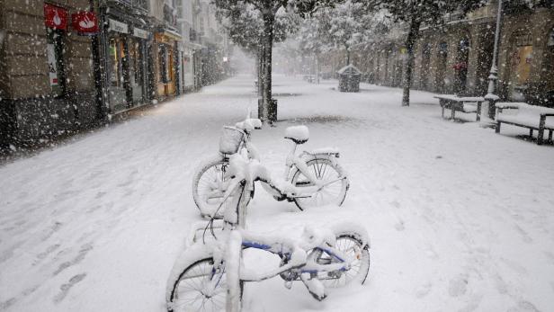 Zwei Fahrräder sind auf einer verschneiten Straße abgestellt.