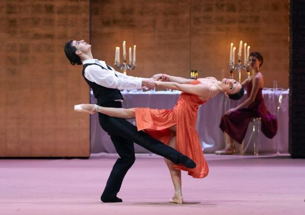 Ein Balletttänzerpaar tanzt vor einem gedeckten Tisch mit Kerzenleuchtern.