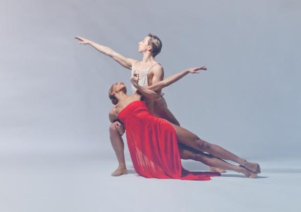 Zwei Balletttänzer in Kostümen führen eine anmutige Pose auf.