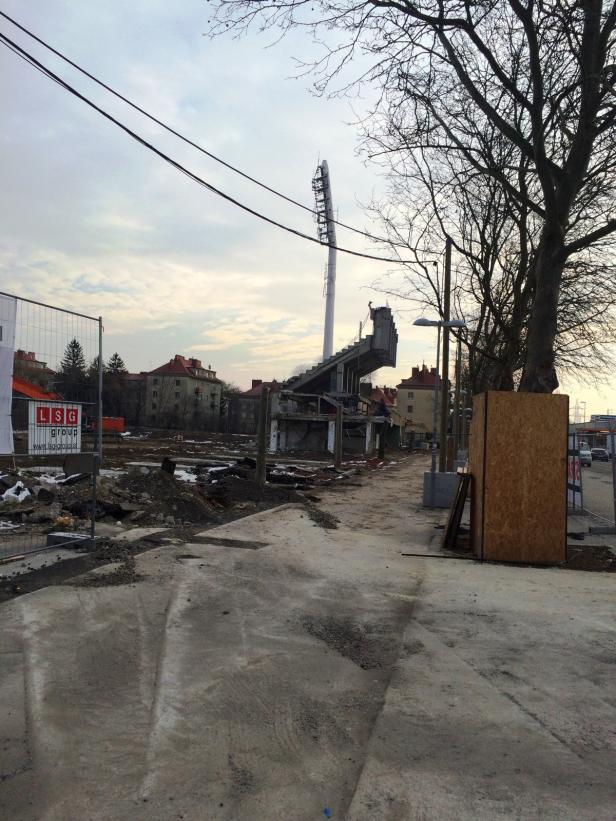 Abrissarbeiten an einem alten Stadion mit Flutlichtmast und Trümmern.