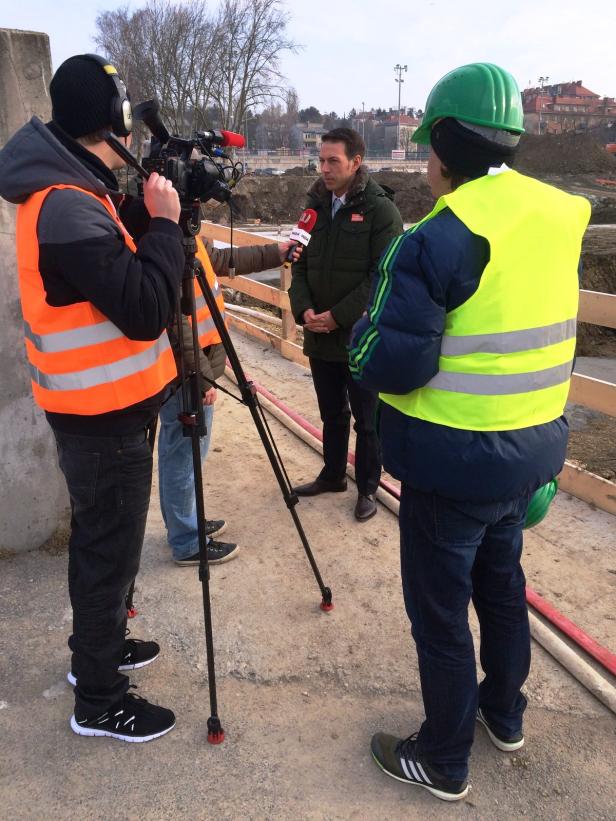 Ein Mann wird von einem Fernsehteam auf einer Baustelle interviewt.
