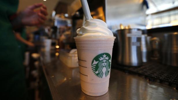 A barista puts whipped cream on a drink at a newly Ein Starbucks Frappuccino mit Schlagsahne steht auf einer Theke.