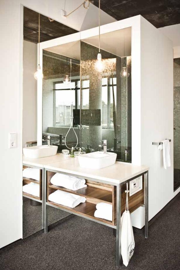 Ein modernes Badezimmer mit Doppelwaschbecken, Spiegelwand und Handtüchern.