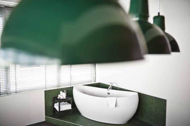Ein Badezimmer mit einer freistehenden Badewanne und grünen Akzenten.