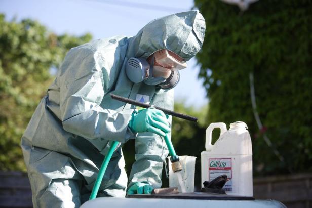 Eine Person in Schutzkleidung hantiert mit einer Chemikalie namens Callisto.