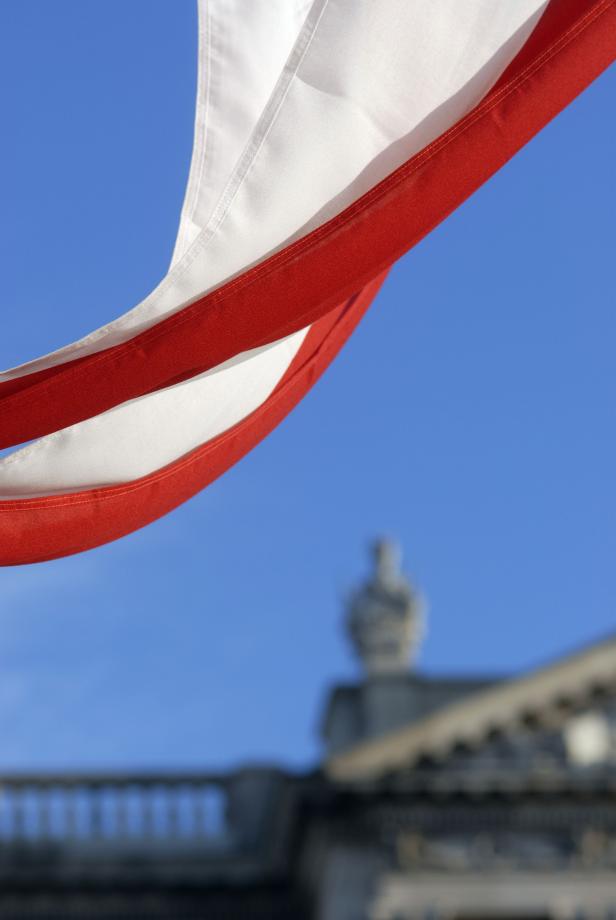Eine rot-weiße Flagge weht vor einem Gebäude unter blauem Himmel.