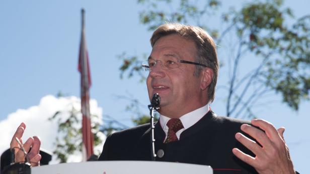 Ein Mann in Tracht hält eine Rede vor einer bayerischen Flagge.