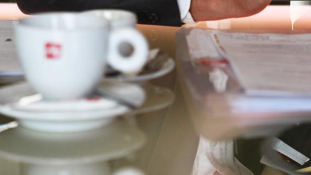 Eine Kaffeetasse steht auf einem Tisch neben Dokumenten.