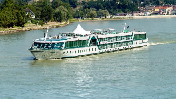 Ein Flusskreuzfahrtschiff fährt auf einem Fluss entlang.