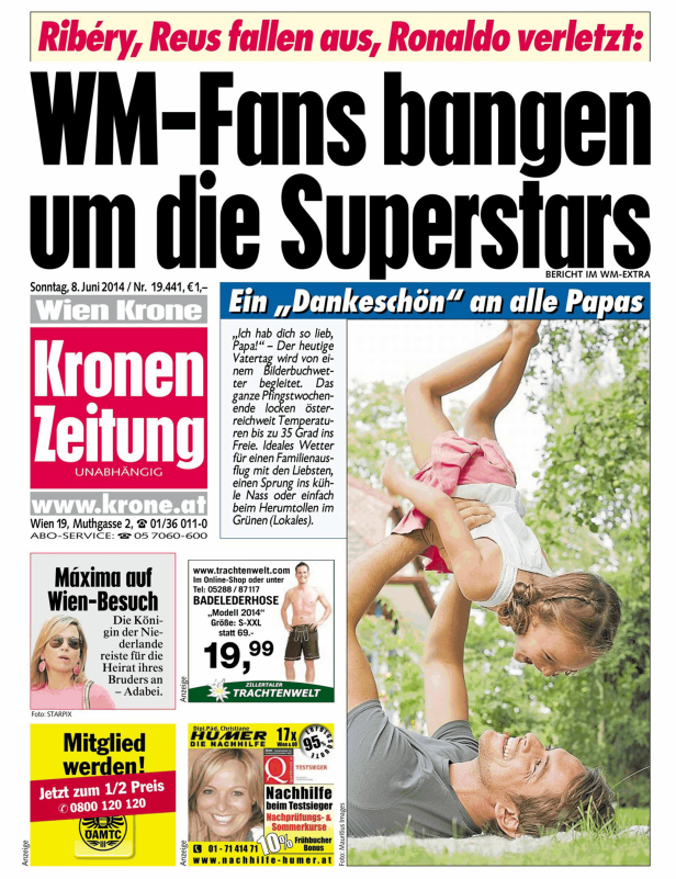 Ein Vater liegt auf einer Wiese und hält seine lachende Tochter in der Luft.