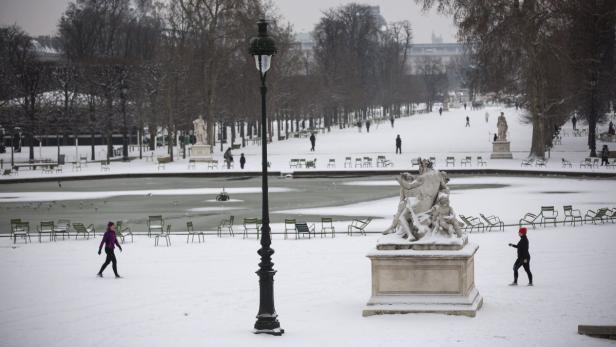 Der Jardin du Luxembourg in Paris unter einer Schneedecke mit Menschen und Statuen.