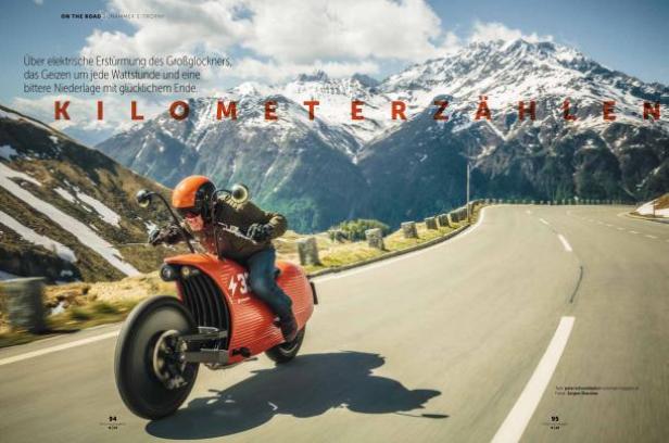 Ein Mann fährt mit einem orangefarbenen Motorrad auf einer Bergstraße.