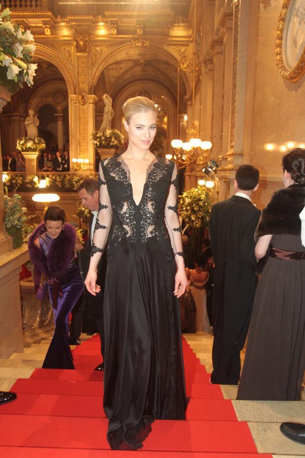 Eine Frau in einem schwarzen Kleid auf einer roten Treppe.