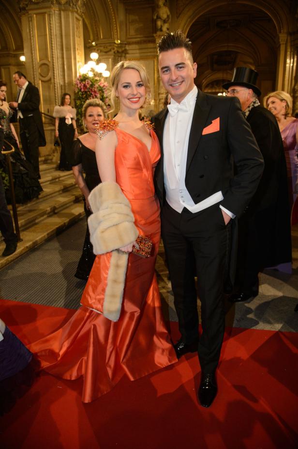 Ein Paar in Abendgarderobe auf einem roten Teppich bei einer Veranstaltung.