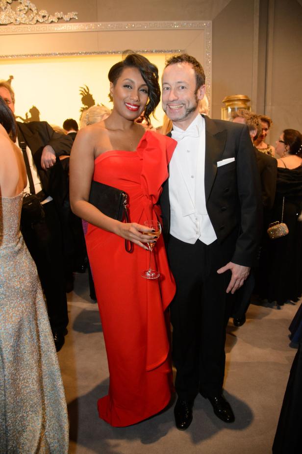 Eine Frau in einem roten Kleid und ein Mann im Smoking posieren für ein Foto.