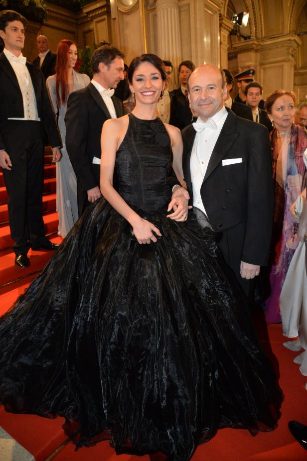 Eine Frau in einem schwarzen Abendkleid mit einem Mann im Smoking auf einem roten Teppich.