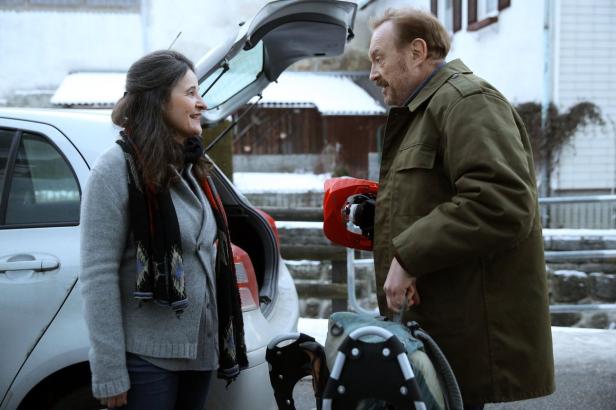 Ein Mann und eine Frau packen Schneeschuhe in den Kofferraum eines Autos.