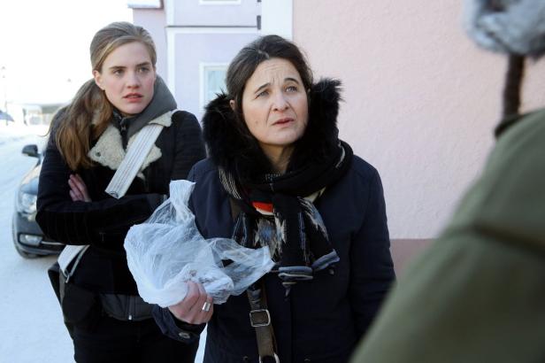 Zwei Frauen stehen im Winter draußen, eine hält eine Plastiktüte in der Hand.