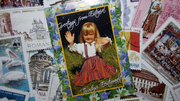 Eine Postkarte mit einem Mädchen in estnischer Tracht, umgeben von Briefmarken.