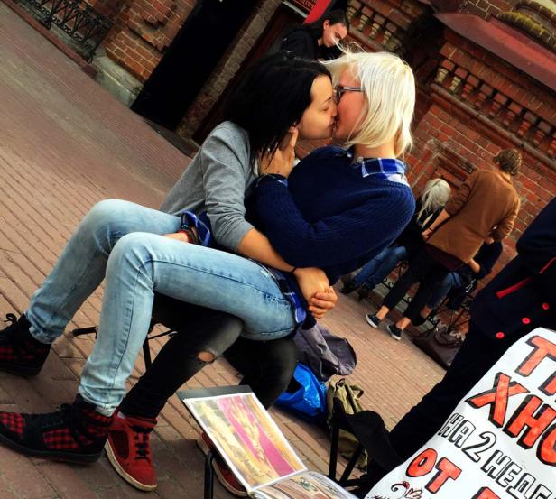 Zwei Frauen sitzen auf der Straße und küssen sich.