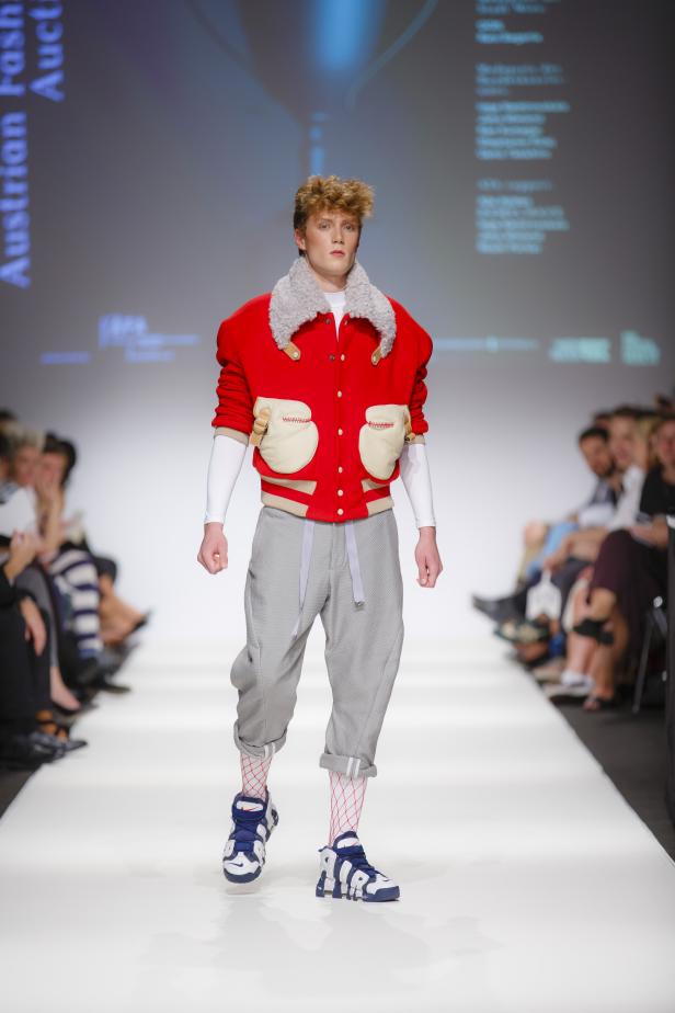 Ein junger Mann präsentiert Mode auf einem Laufsteg.