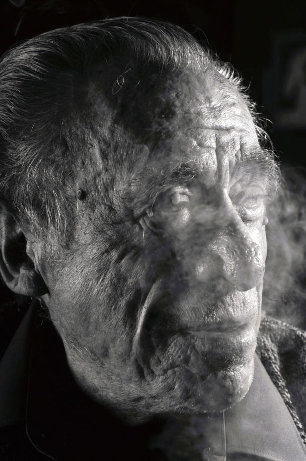 Ein älterer Mann mit Falten raucht eine Zigarette.