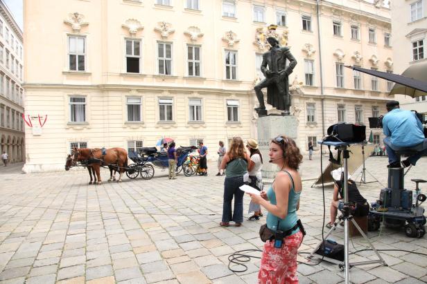 Ein Filmteam dreht eine Szene mit einer Pferdekutsche auf einem Platz in Wien.