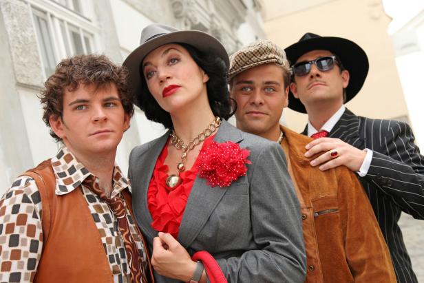 Vier Personen in Retro-Kleidung posieren für ein Foto.