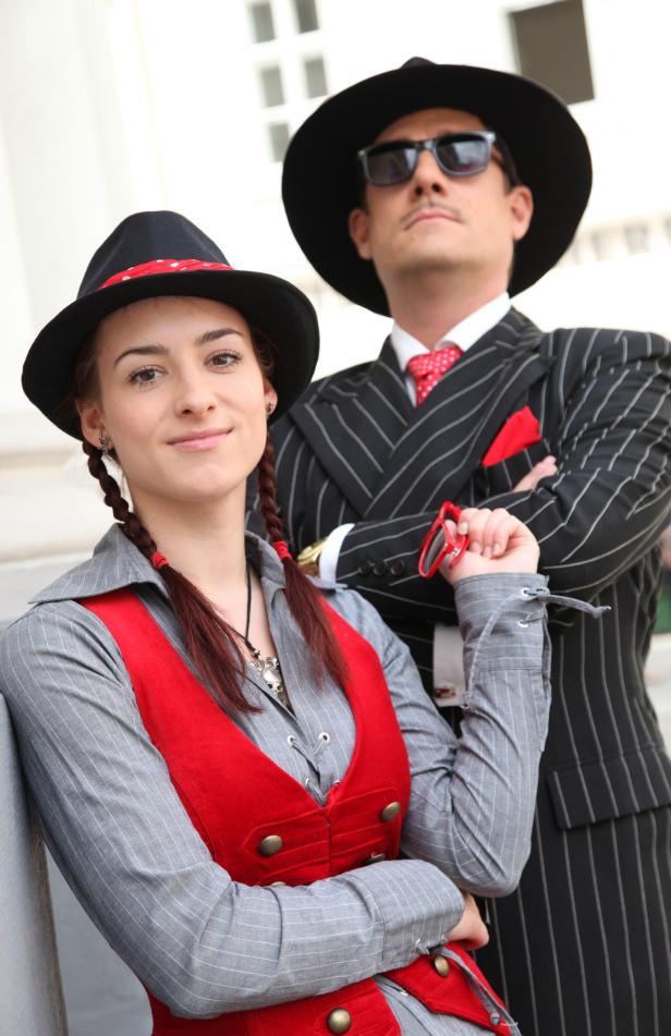 Eine Frau im Dirndl-Stil und ein Mann im Nadelstreifenanzug posieren.