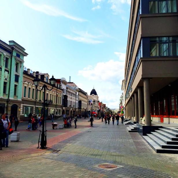 Eine belebte Fußgängerzone mit historischen Gebäuden und einem modernen Bürogebäude.