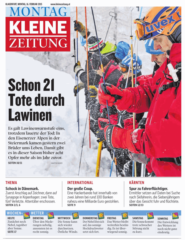 Skifahrer steigen in winterlicher Umgebung mit Seilen und Stöcken einen Hang hinauf.