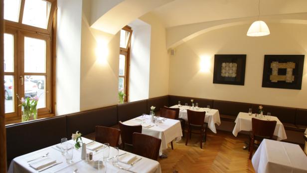 Ein Speisesaal mit gedeckten Tischen und braunen Holzbänken.