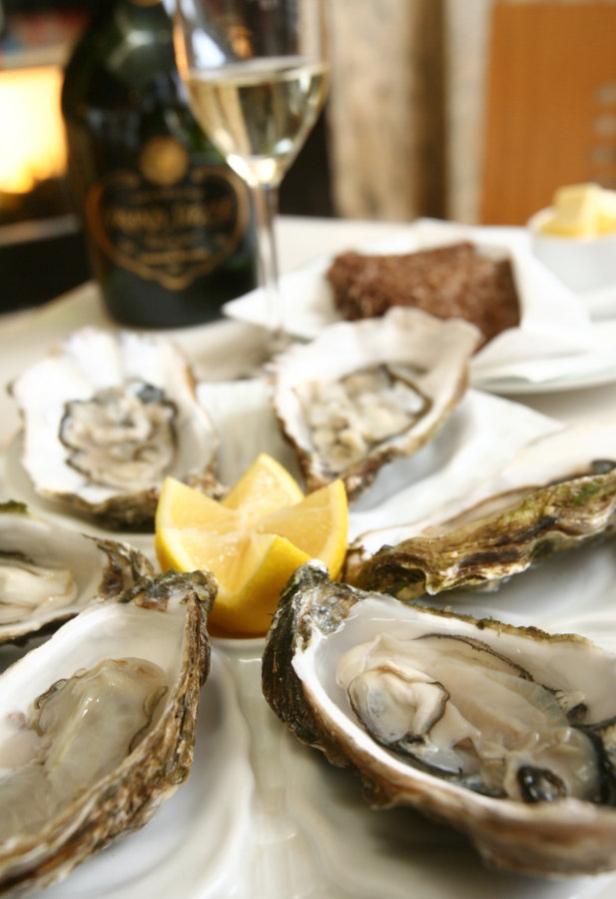 Eine Platte mit frischen Austern und Zitronenspalten, dazu Champagner und Brot.