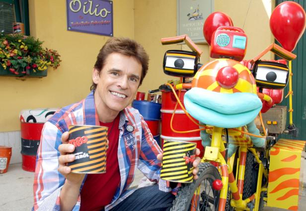 Ein Mann lächelt neben einem fantasievollen, gelb-roten Fahrrad mit Ballon und Deko.
