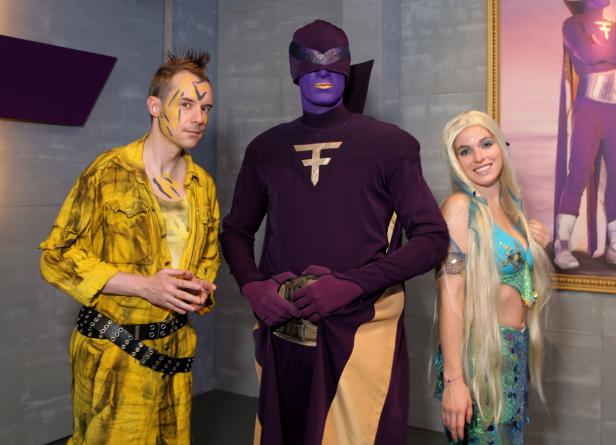 Drei Personen in Kostümen posieren für ein Foto.