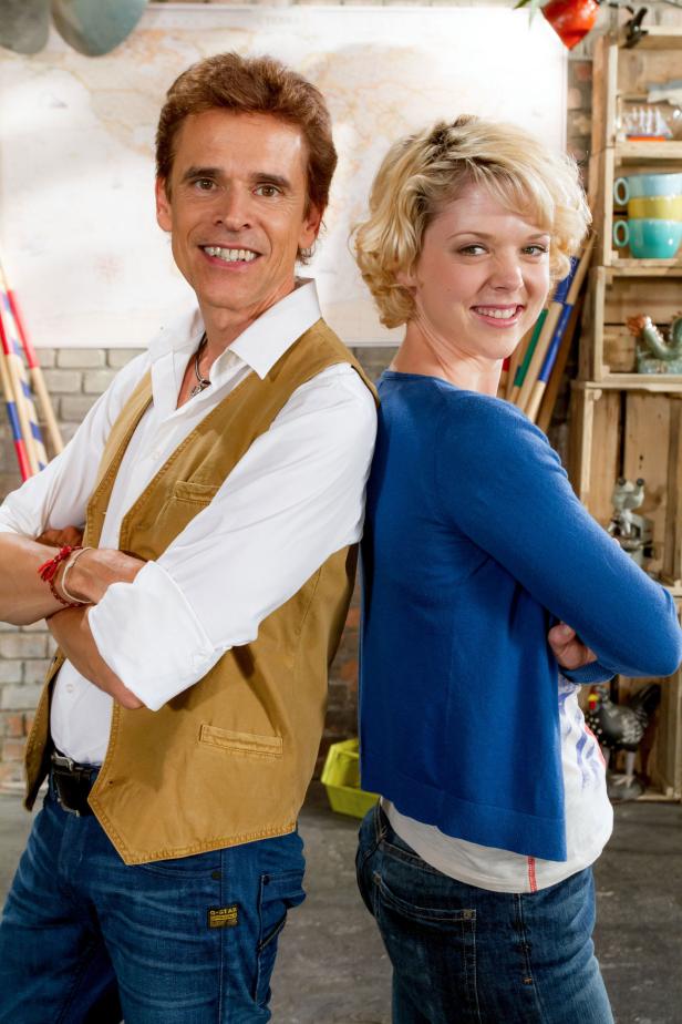 Ein Mann und eine Frau stehen Rücken an Rücken und lächeln.