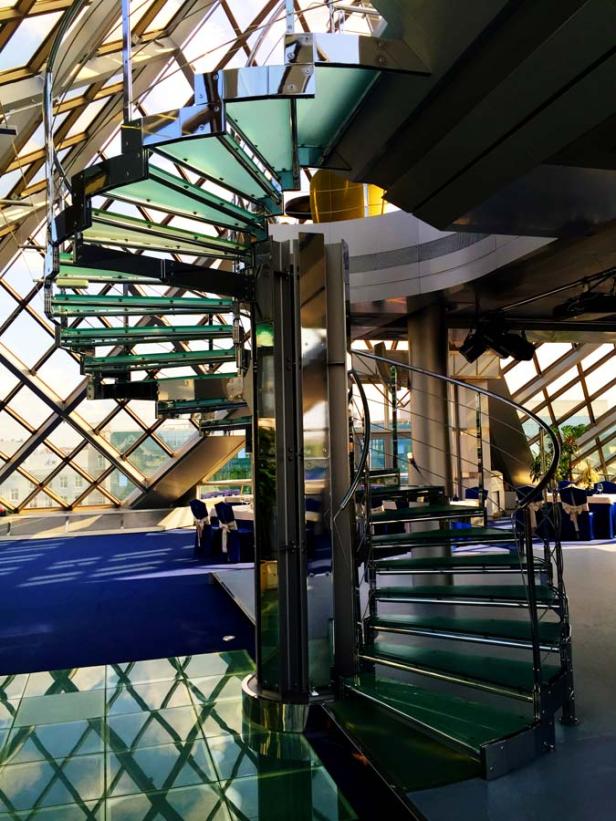 Eine Wendeltreppe aus Glas und Stahl in einem modernen Gebäude.