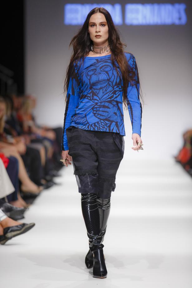 Eine Frau mit langen Haaren präsentiert Mode auf einem Laufsteg.