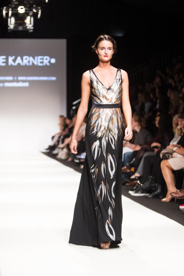 Eine Frau präsentiert ein langes, ärmelloses Kleid auf einem Laufsteg.