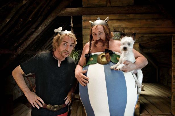 Asterix und Obelix posieren mit Idefix in einem Dachboden.