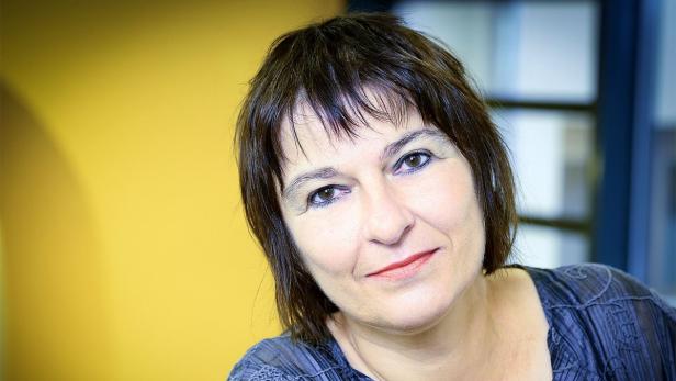 Eine Frau mit braunen Haaren lächelt in die Kamera.