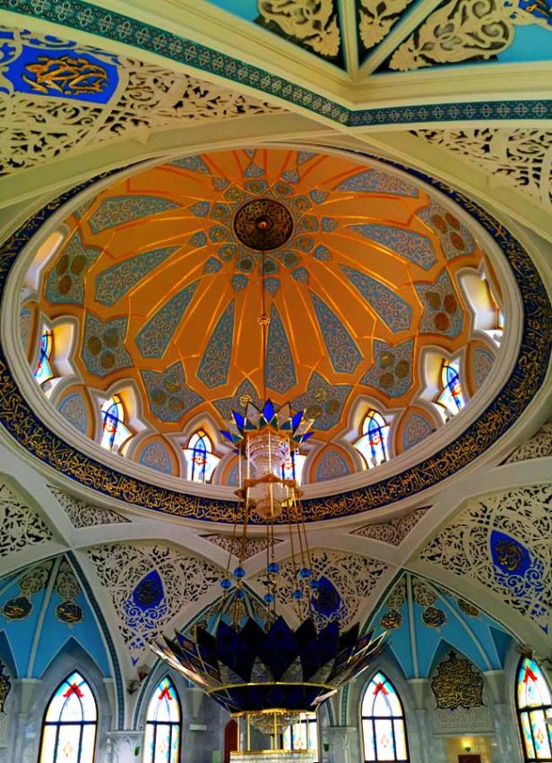 Blick in die kunstvoll verzierte Kuppel einer Moschee mit einem großen Kronleuchter.