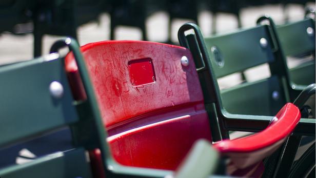 Eine Reihe von grünen Stadionsitzen mit einem roten Sitz im Vordergrund.