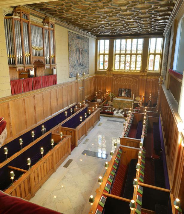 Innenansicht einer Kapelle mit Orgel, Holzbänken und einem Altar.