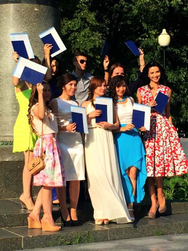 Eine Gruppe junger Absolventen posiert mit ihren Diplomen für ein Foto.