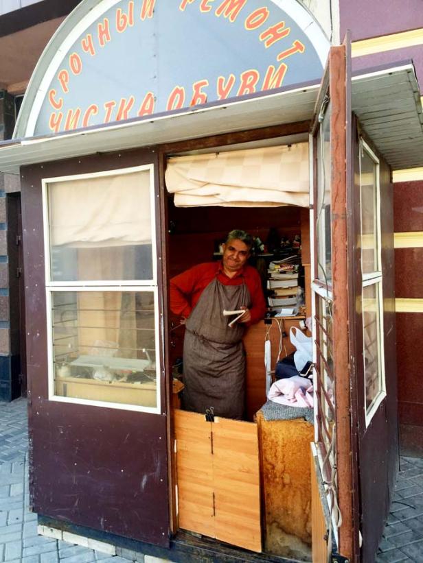 Ein Schuhmacher steht in seinem kleinen Laden.