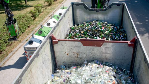 Ein Kran leert Glasmüll in einen Container.